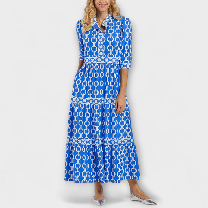 A woman wearing a flowing chain print midi dress that drapes elegantly as she walks.