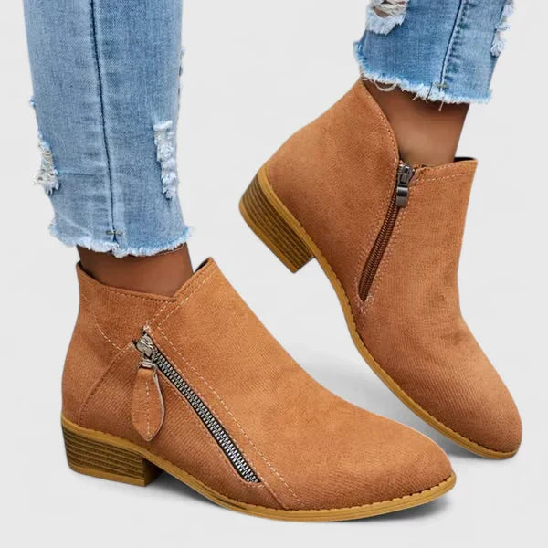 Woman wearing light blue vintage-style ankle boots, walking along a leafy street.