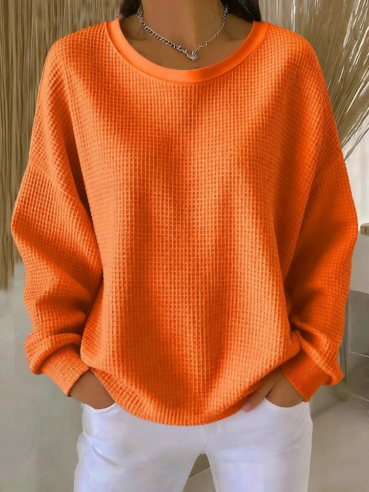A woman wearing a relaxed-fit waffle-stitch jumper in soft pink with a textured surface