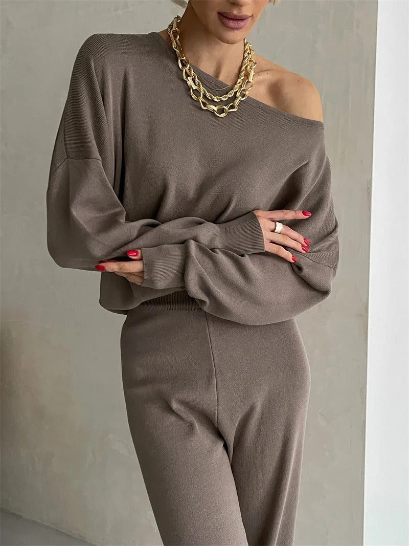 A woman wearing an off-shoulder draped top with wide-leg trousers
