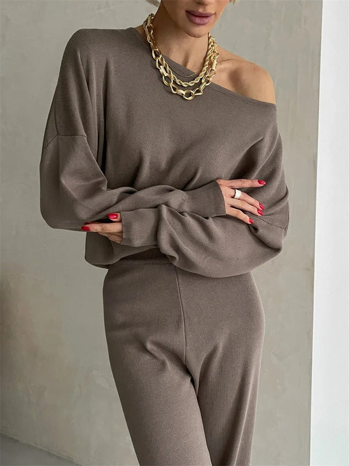 A woman wearing an off-shoulder draped top with wide-leg trousers