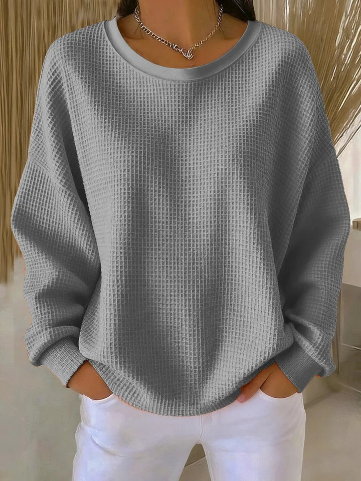 A woman wearing a relaxed-fit waffle-stitch jumper in soft pink with a textured surface