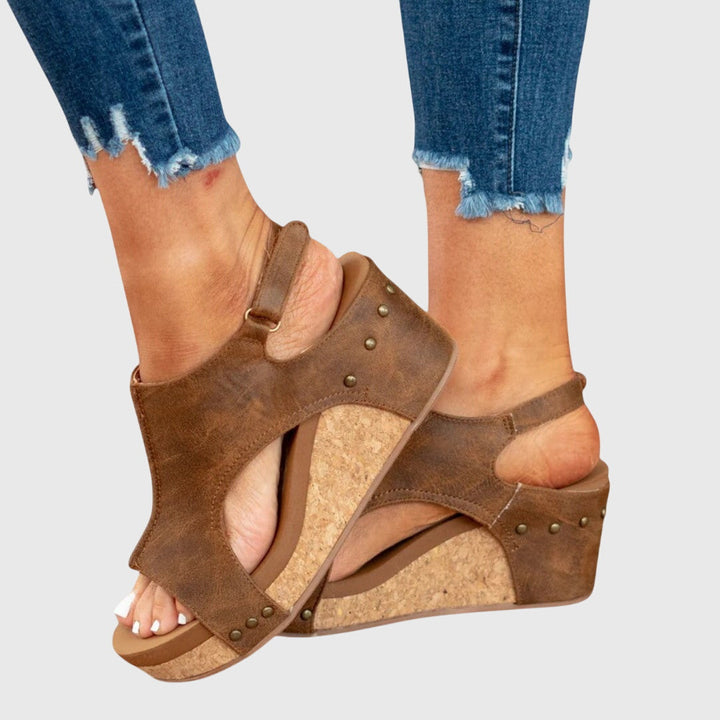 A woman in taupe wedge sandals with an open front, out shopping on a warm day.