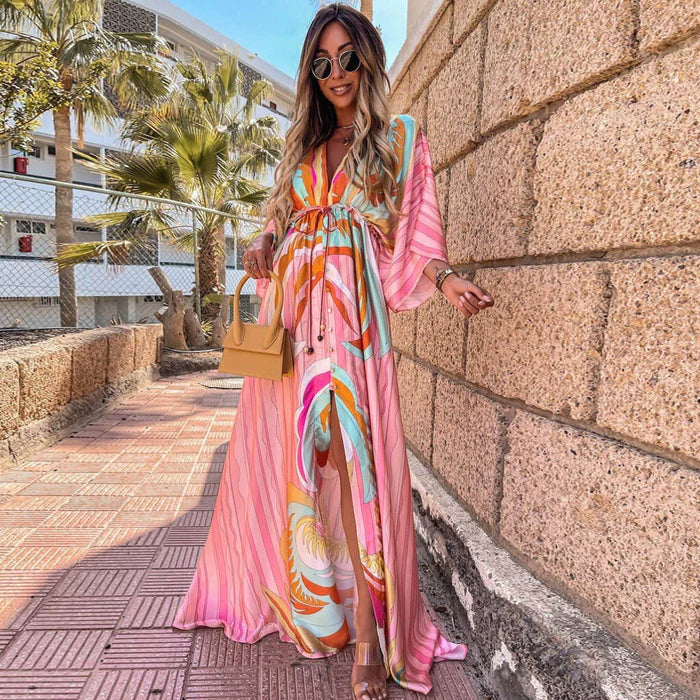 Woman wearing a colourful abstract print kaftan maxi dress with flowing sleeves by the water.
