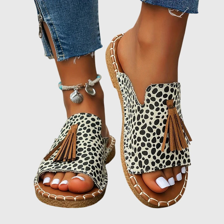 A woman wearing colourful patterned boho slides with tassel details on a holiday day out.
