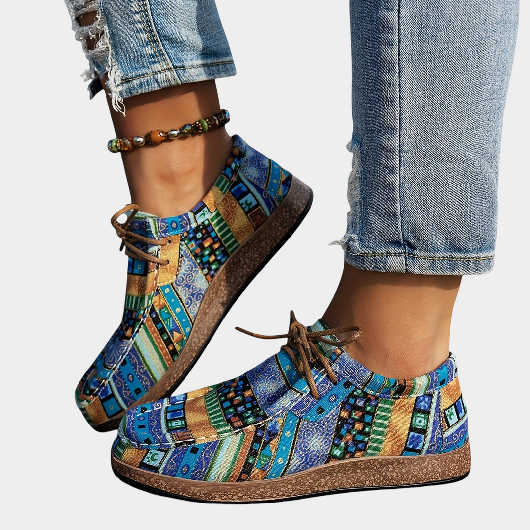 A woman wearing blue boho-print lace-up comfort trainers while out walking.