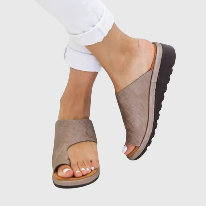 A woman in gold supportive sandals standing gracefully, feet cushioned and at ease.