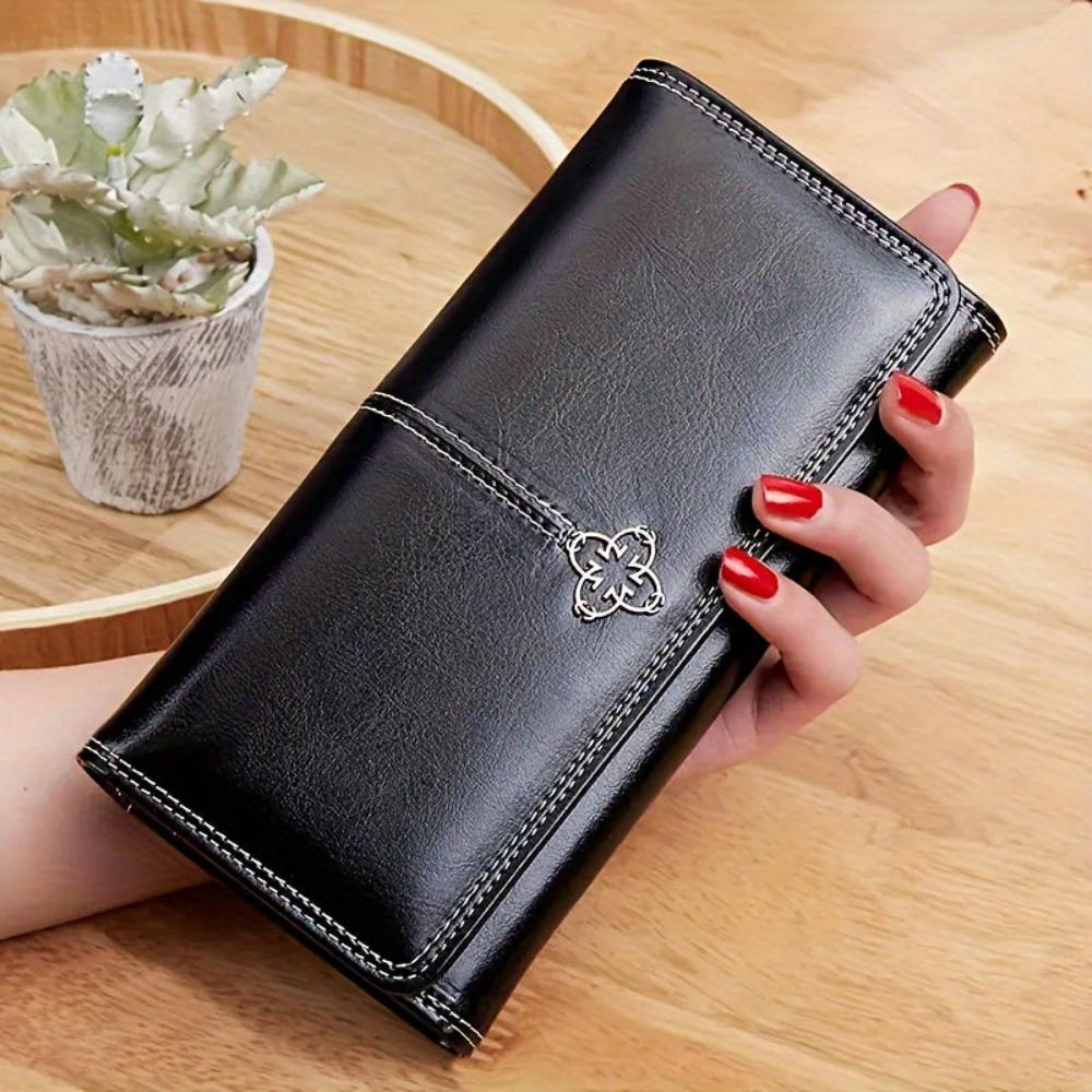 A woman holding an open bifold wallet, tucking a card into its slot.