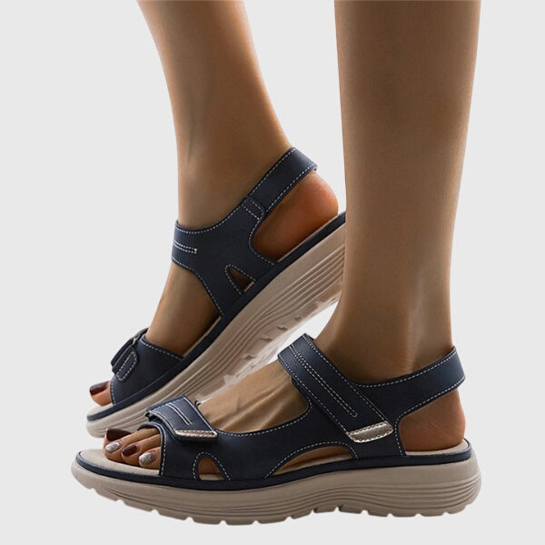 A woman in beige adjustable strap sandals standing steady and relaxed on a sunny path.