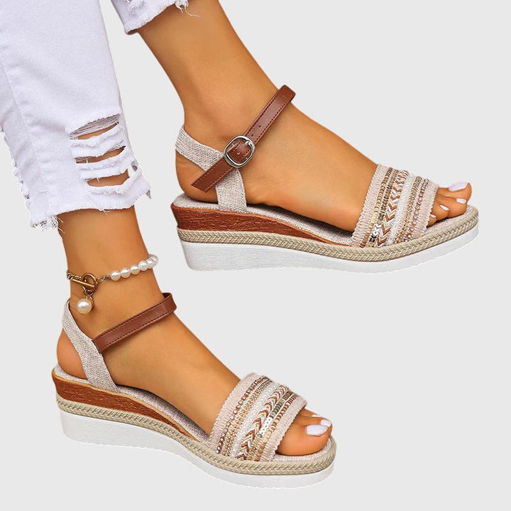 A woman walking easily in lightweight modern sandals in a soft white and brown finish.