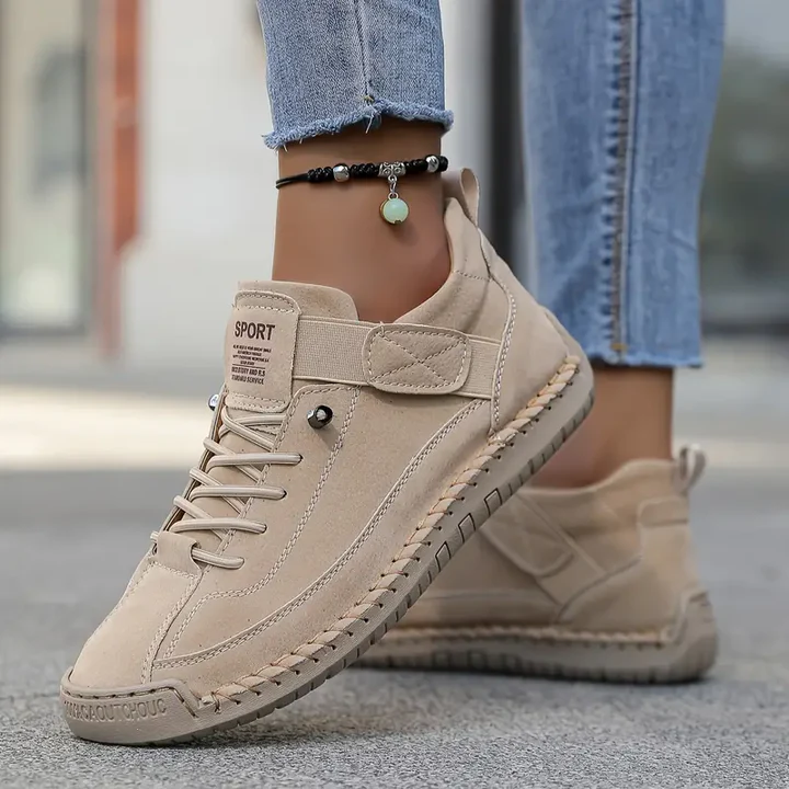 A woman wearing white lace-up orthopaedic trainers with an adjustable strap.