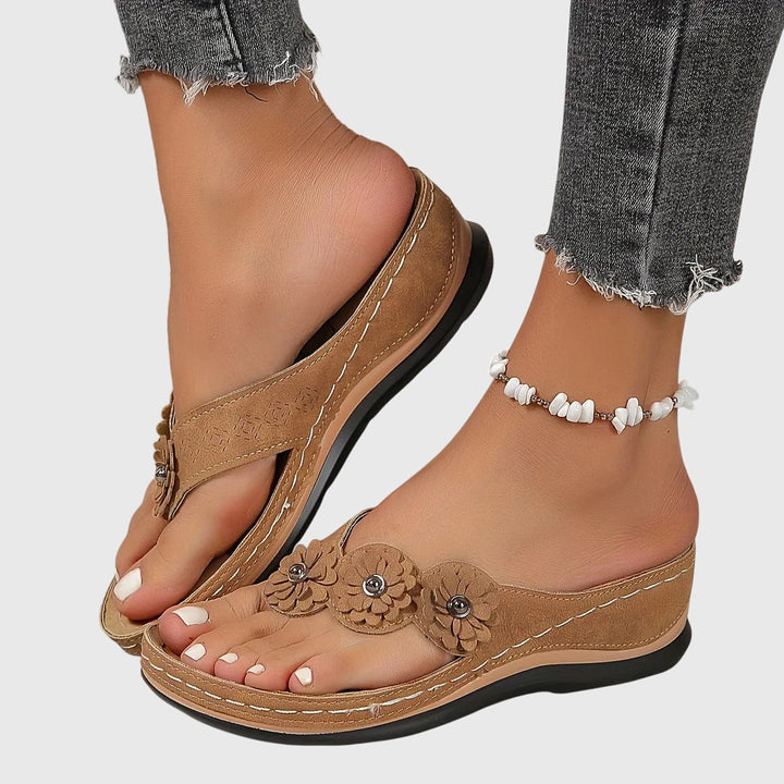 A woman wearing navy cushioned flip-flops with a supportive insole and open-front design.
