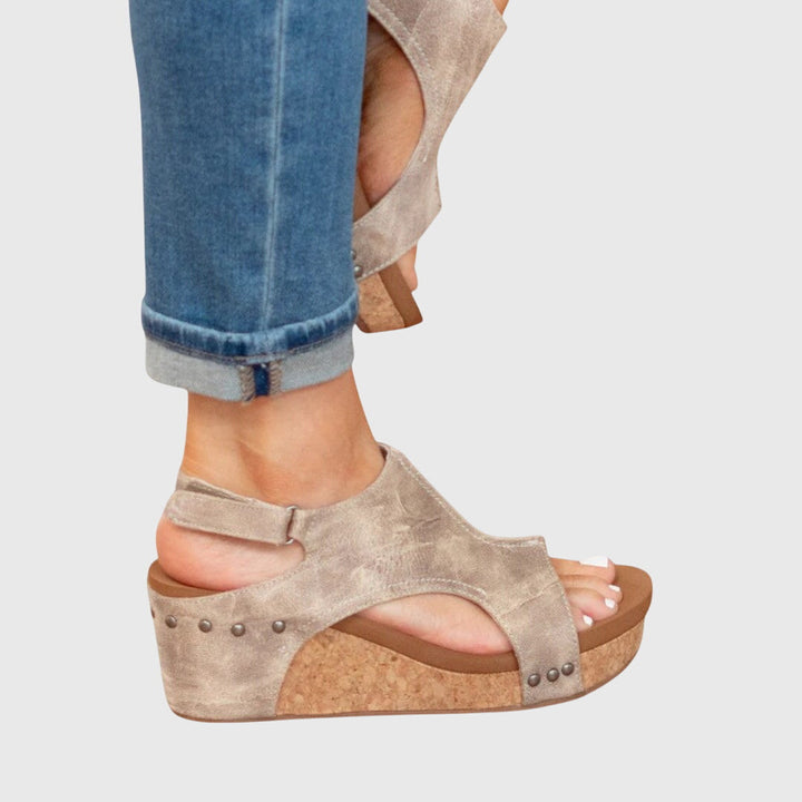 A woman in taupe wedge sandals with an open front, out shopping on a warm day.
