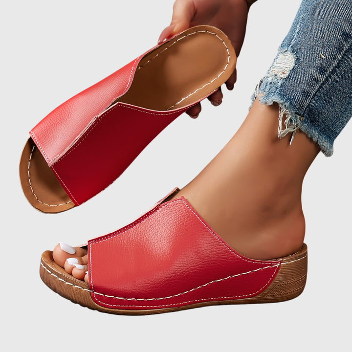 A woman wearing black platform slides on a relaxed day out.