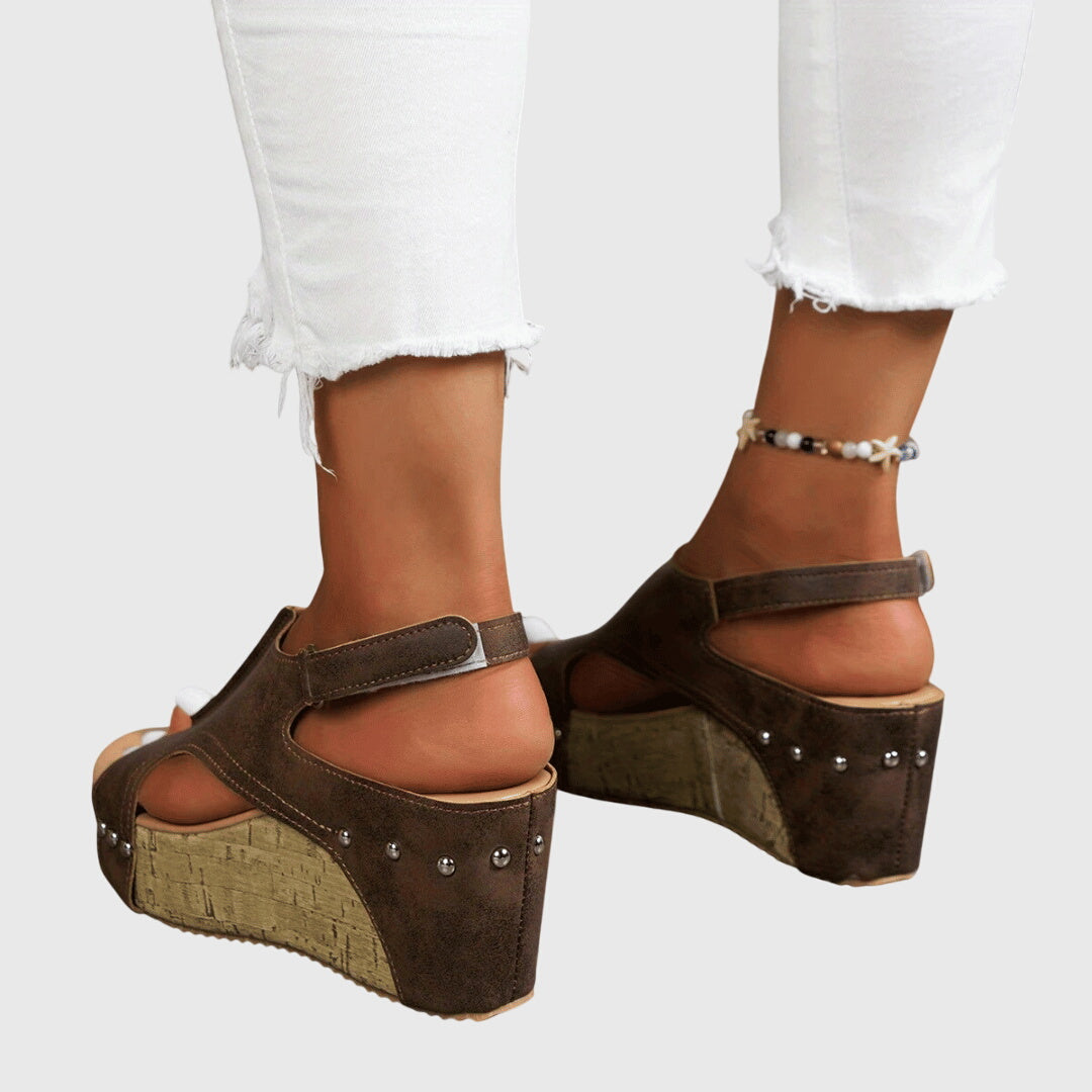 A woman in studded wedge sandals with an open front at a summer event.