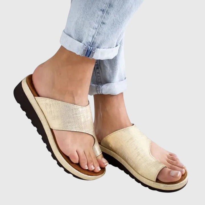 A woman in gold supportive sandals standing gracefully, feet cushioned and at ease.