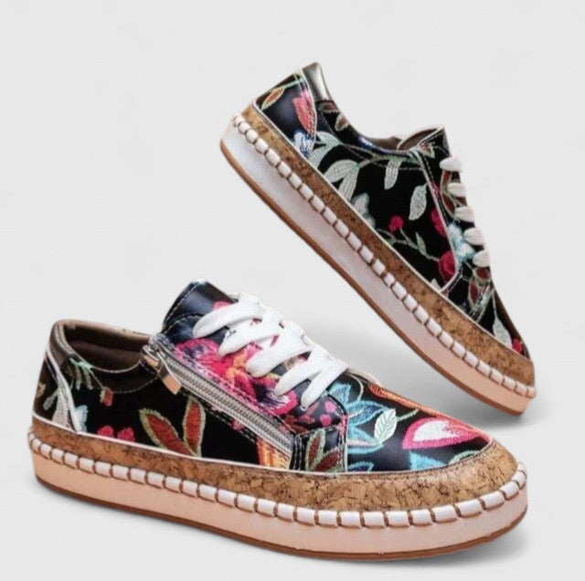 A woman wearing floral lace-up orthopaedic trainers with a side zip and platform sole.