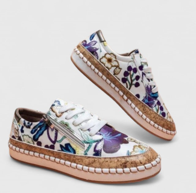 A woman wearing floral lace-up orthopaedic trainers with a side zip and platform sole.