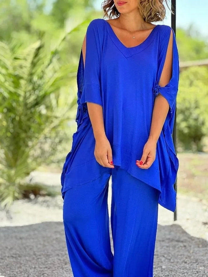 A woman wearing a draped top with shoulder cut-out details and matching wide trousers.