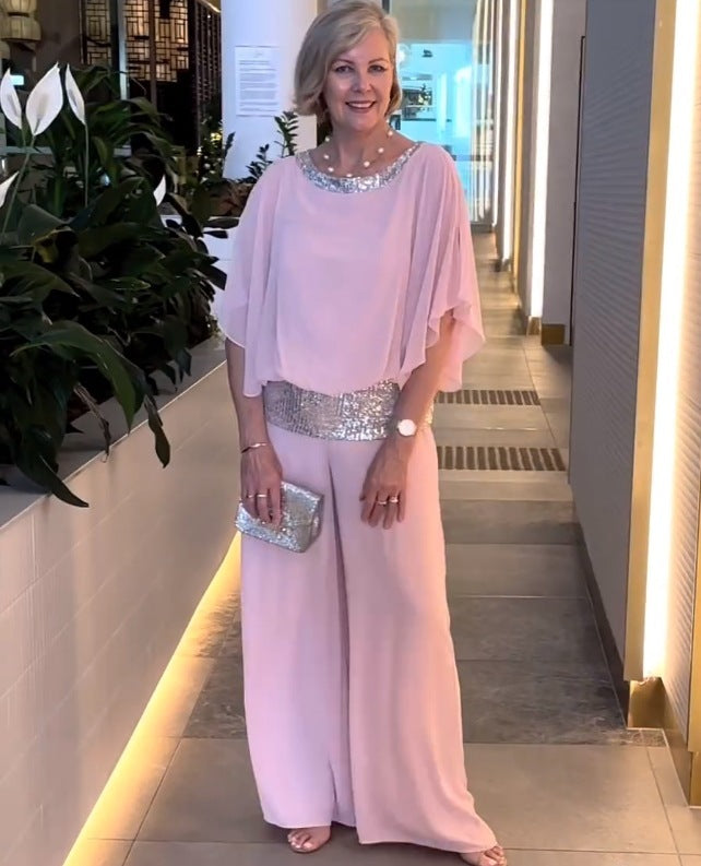 A woman wearing an embellished blouse-style top with softly flowing wide evening trousers.