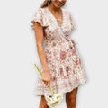 A white floral boho short summer dress with floaty sleeves, styled for a sunny outdoor occasion