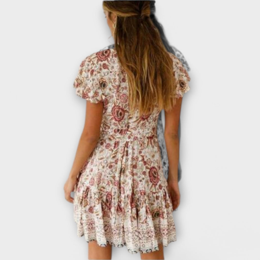 A white floral boho short summer dress with floaty sleeves, styled for a sunny outdoor occasion