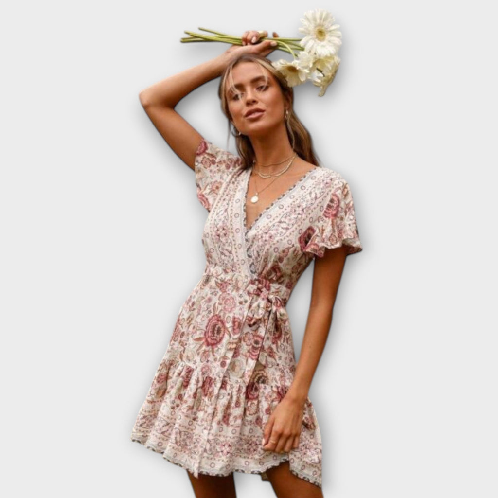 A white floral boho short summer dress with floaty sleeves, styled for a sunny outdoor occasion