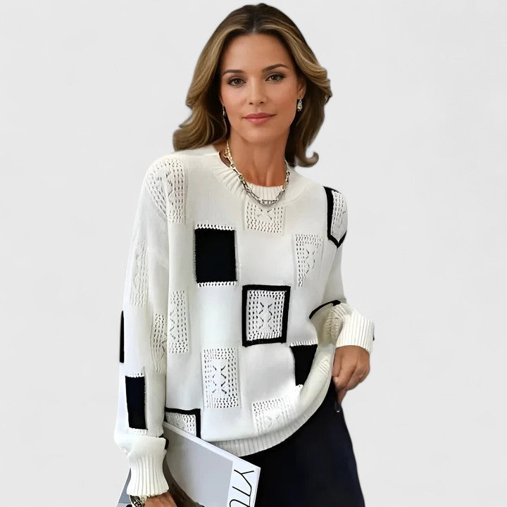 A woman wearing a white jumper with playful openwork detailing and a round neck.