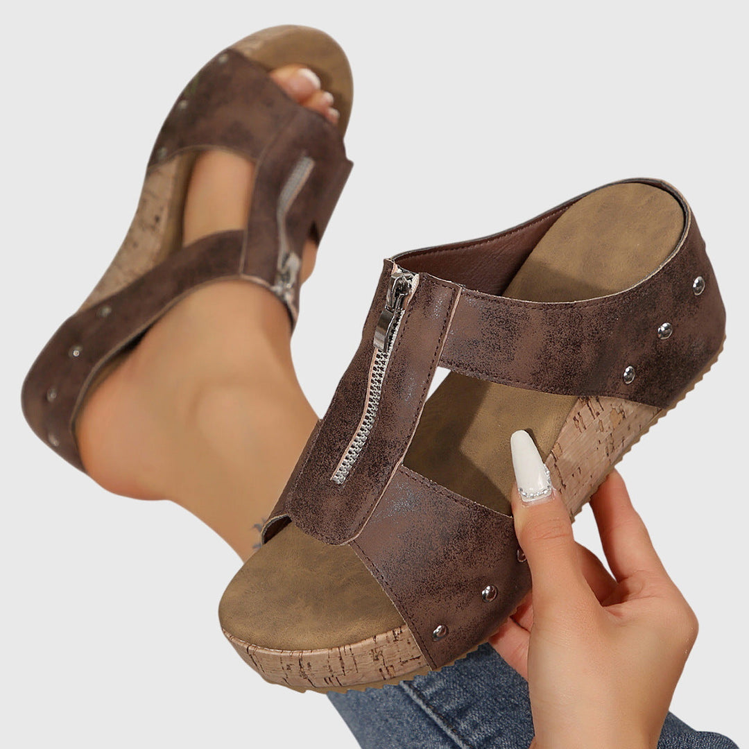 A woman standing comfortably in brown supportive sandals with an adjustable strap and cushioned sole.