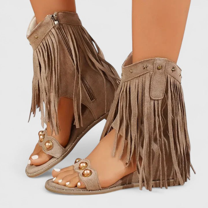 A woman wearing black fringe-detail sandals with a cushioned sole and adjustable strap.