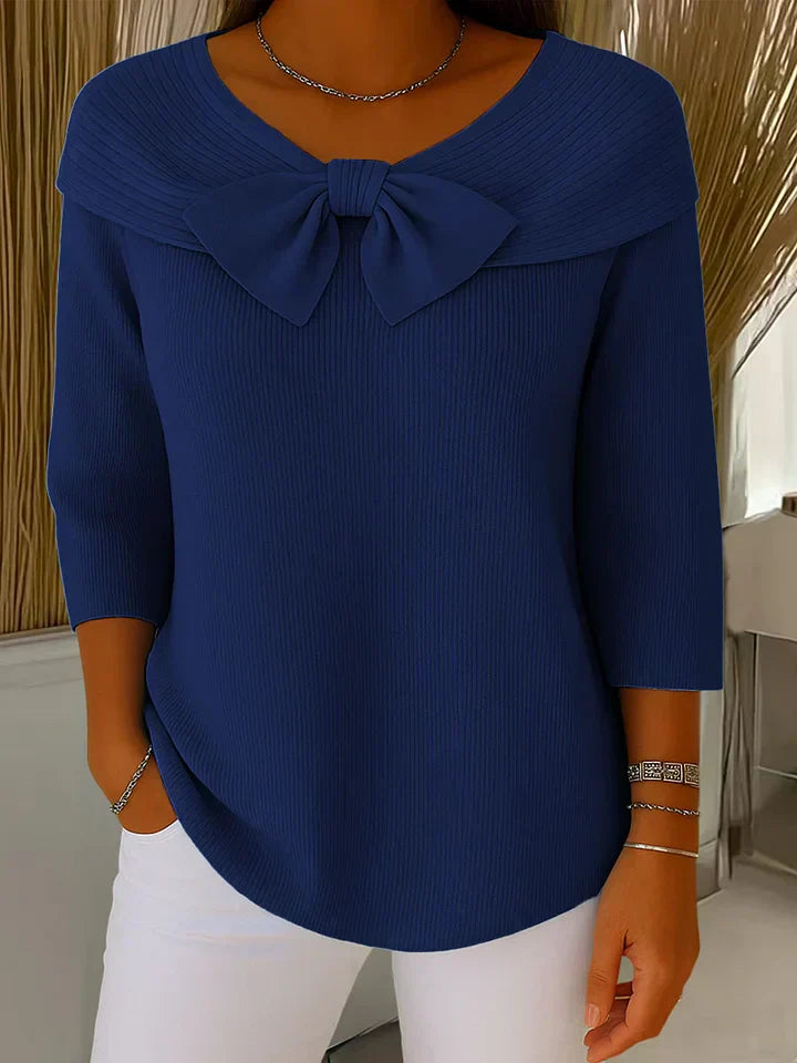A woman wearing a shaped jumper with a soft bow detail, styled for a coffee date.