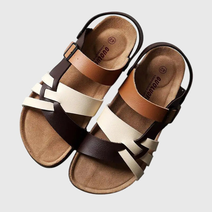 A woman in colourful cross-strap summer sandals with an adjustable ankle buckle on a warm day.