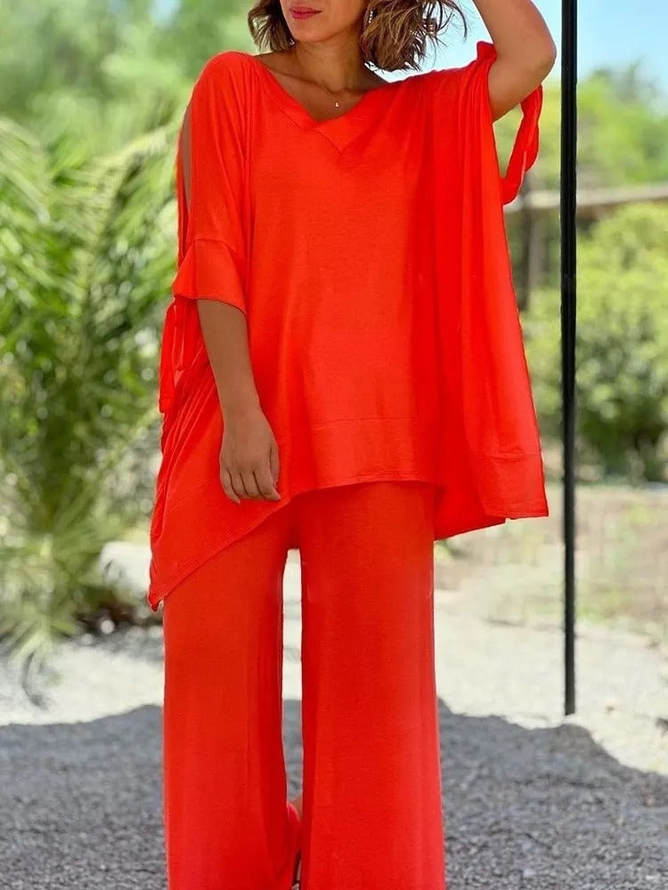 A woman wearing a draped top with shoulder cut-out details and matching wide trousers.
