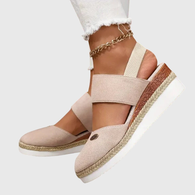 Black closed-toe wedge espadrilles with a wide stretch strap and a braided-trim platform wedge.