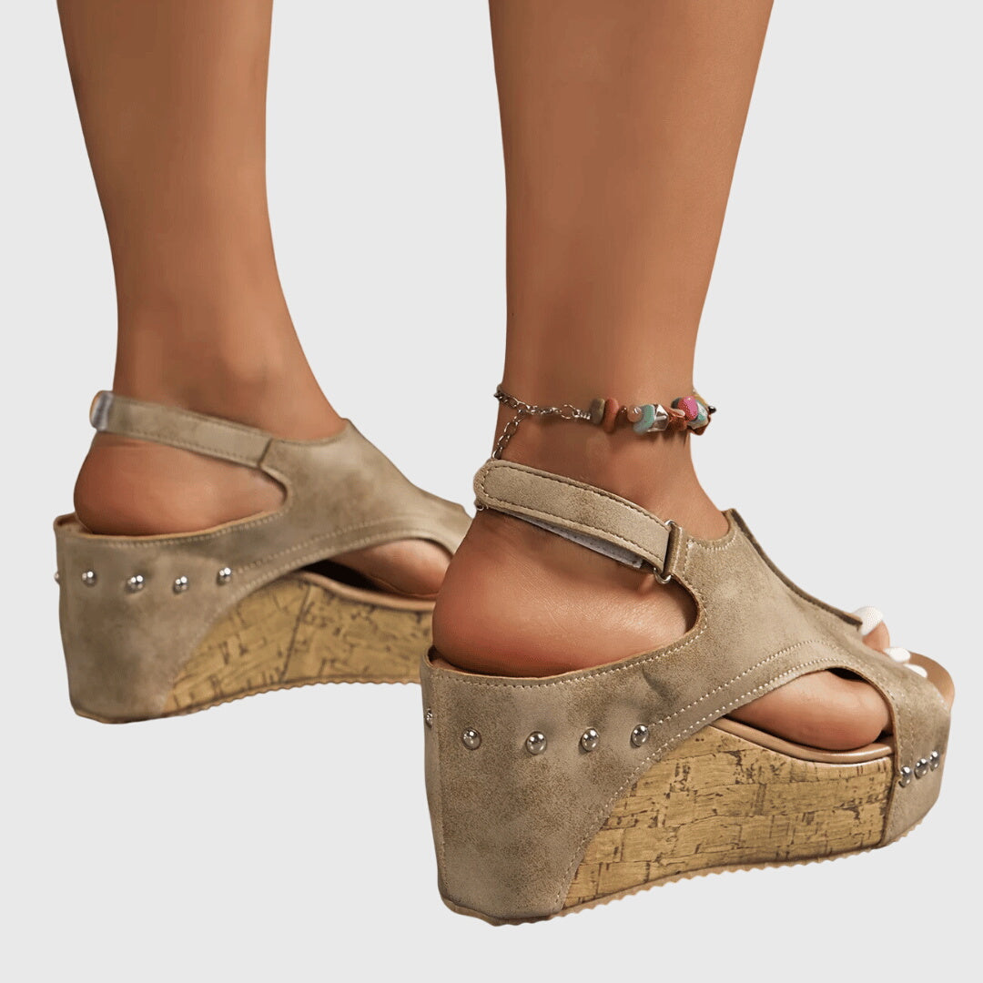A woman in studded wedge sandals with an open front at a summer event.