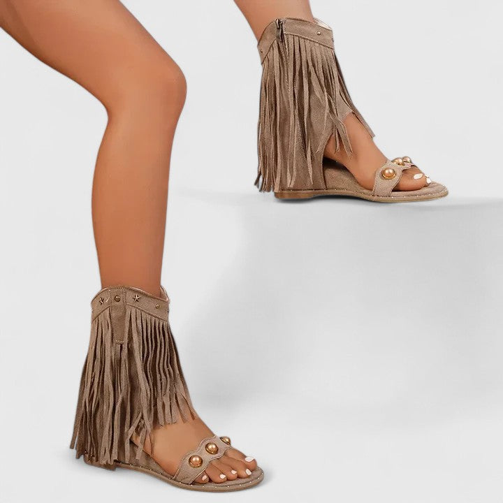 A woman wearing black fringe-detail sandals with a cushioned sole and adjustable strap.