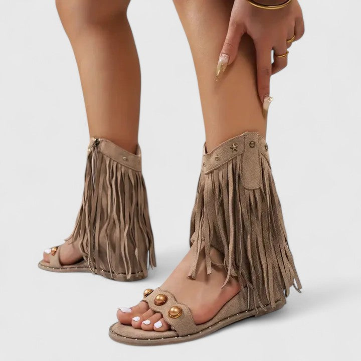 A woman wearing black fringe-detail sandals with a cushioned sole and adjustable strap.