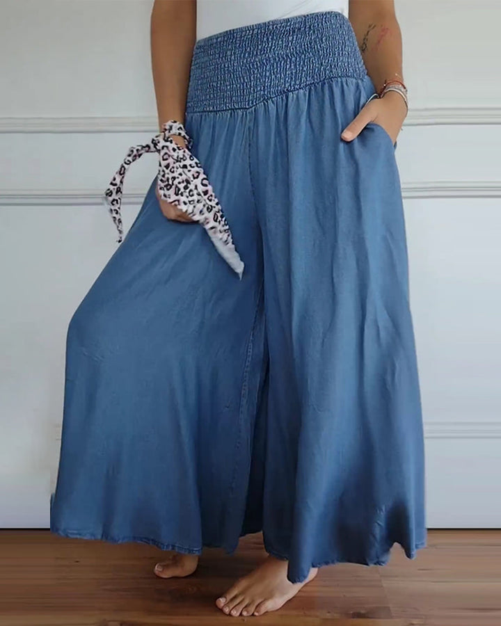 Woman wearing high-waist wide-leg trousers with a tucked-in blouse, mid-stride.