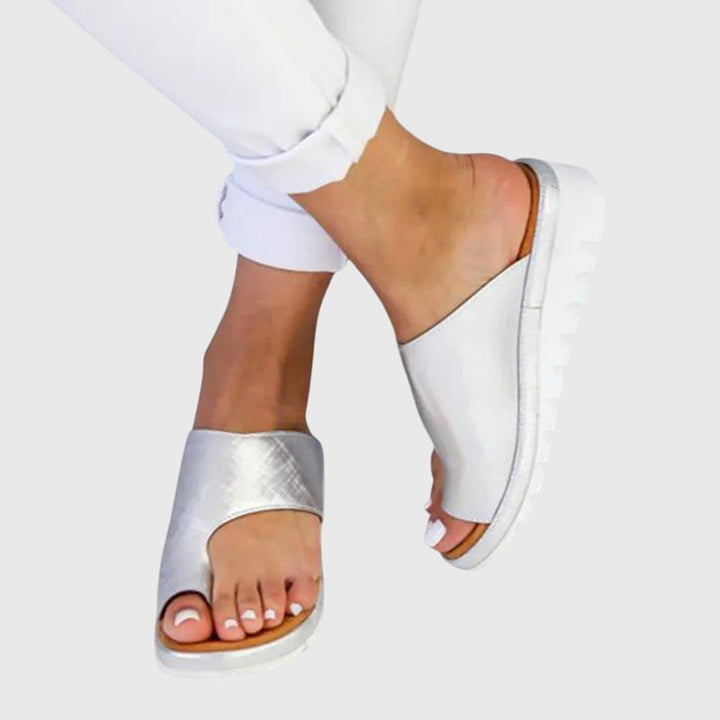 A woman in gold supportive sandals standing gracefully, feet cushioned and at ease.