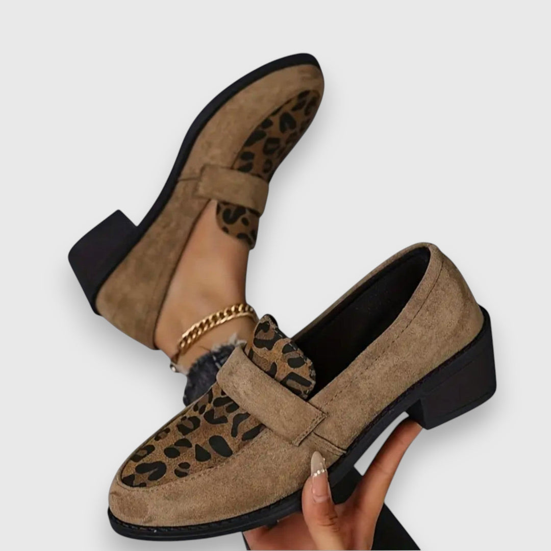 A woman wearing tan leopard print loafers with a low block heel, styled with jeans.