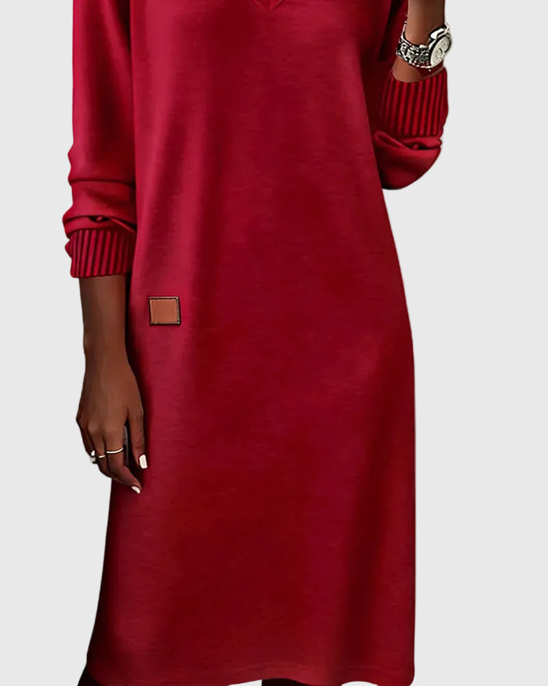 Woman wearing the Emma flowing elegant dress in beige, standing relaxed and smiling.