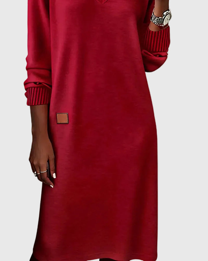 Woman wearing the Emma flowing elegant dress in beige, standing relaxed and smiling.