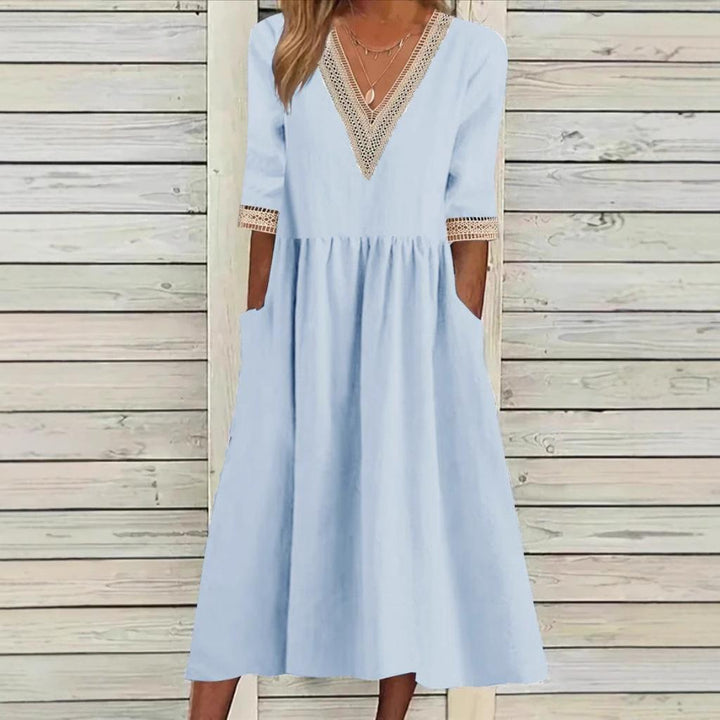 A woman wearing the Deirdre V-neck midi dress with delicate detailing at the collar and sleeves.