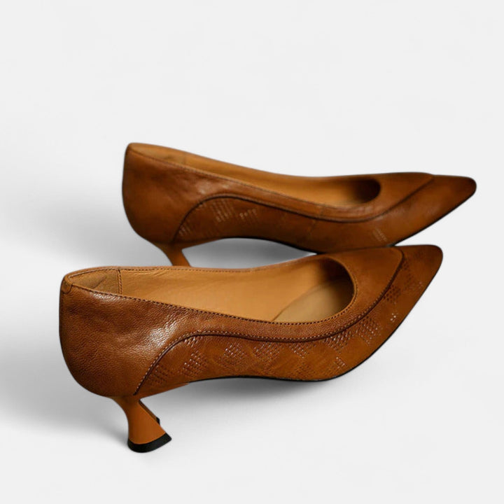 A woman wearing black pointed kitten-heel pumps with a subtle embossed finish.