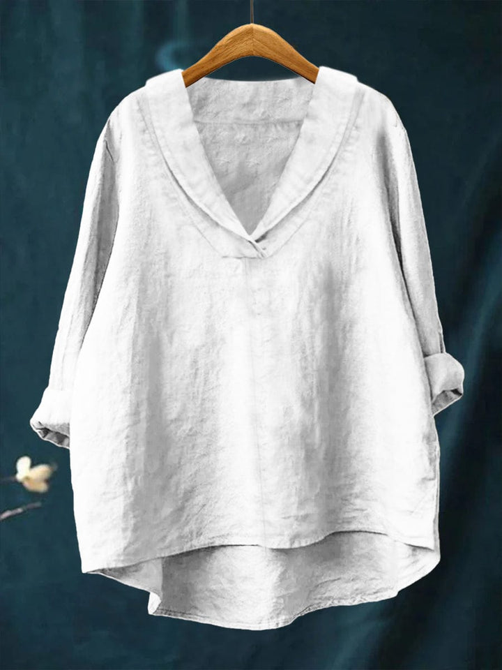A woman wearing an elegant plain summer blouse with a flowing drape, styled with trousers.