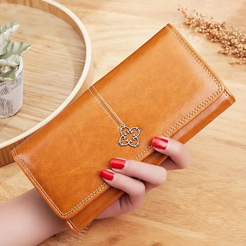 A woman holding a long flap-over wallet, tucking a card into its slot.