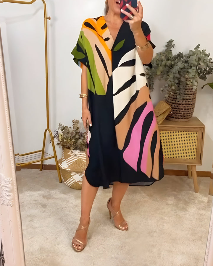 A woman wearing a colourful abstract print dress with a V-neckline and short sleeves.