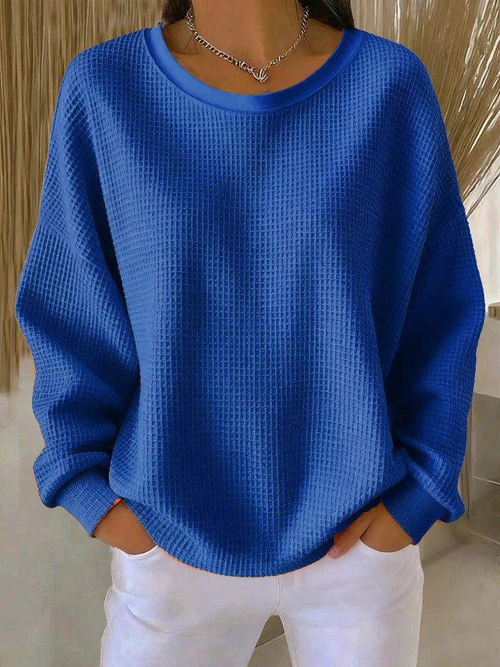 A woman wearing a relaxed-fit waffle-stitch jumper in soft pink with a textured surface