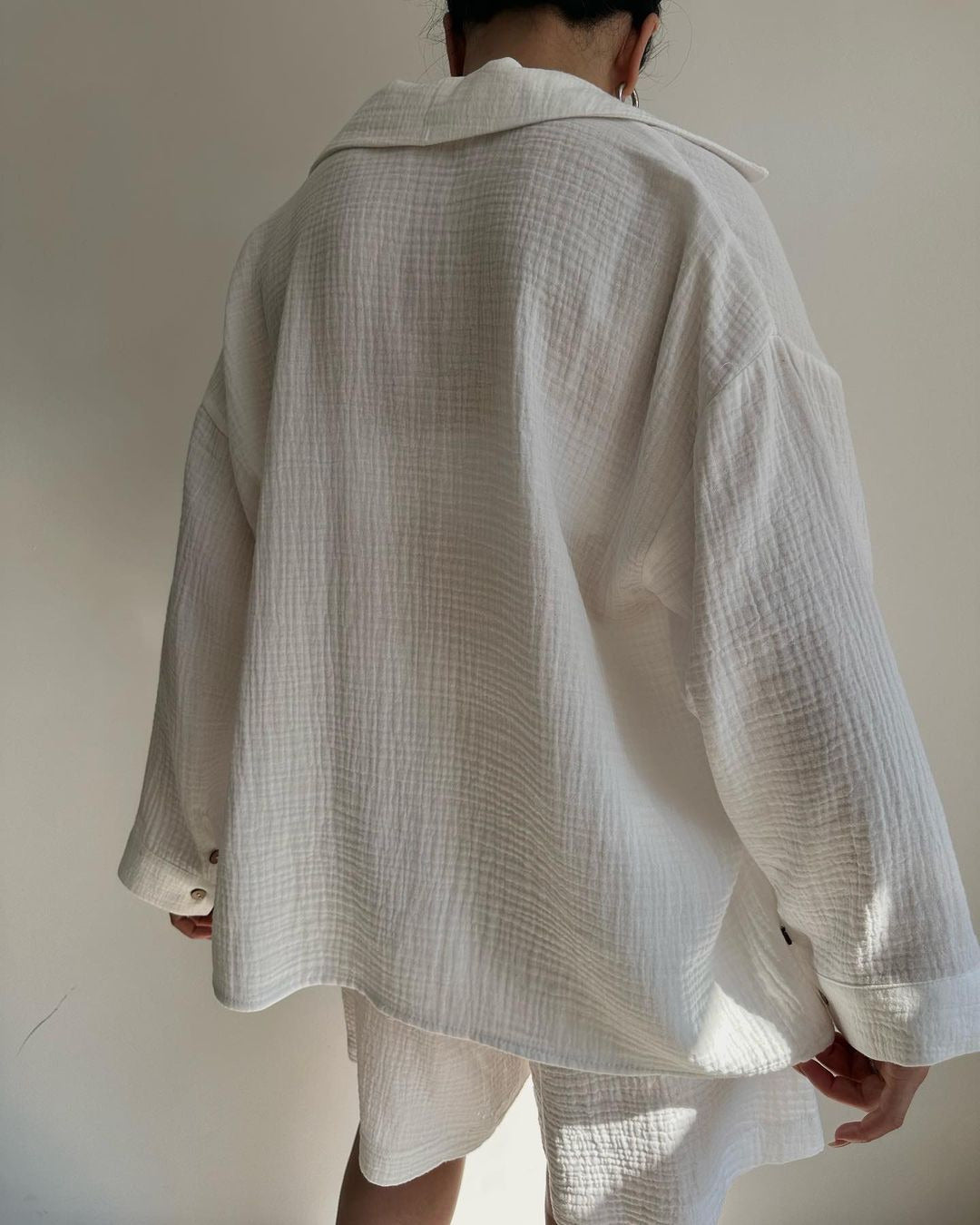 A woman wearing a flowing oversized shirt with drawstring shorts, relaxed and breezy.