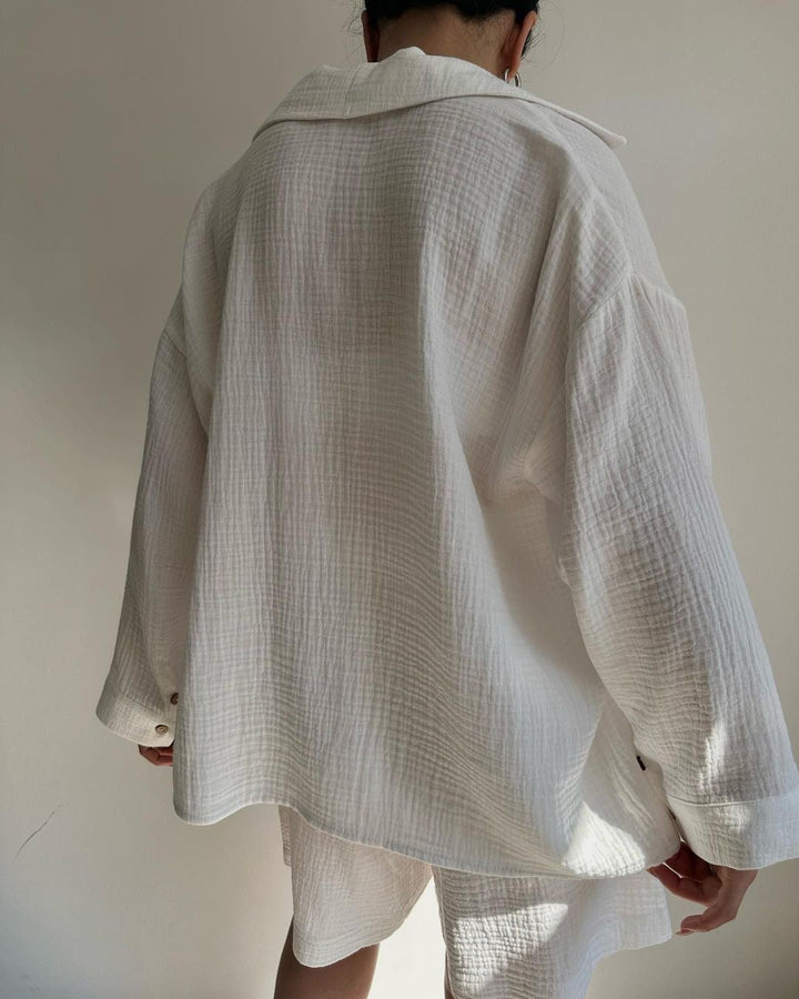 A woman wearing a flowing oversized shirt with drawstring shorts, relaxed and breezy.